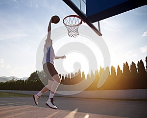 Young man jumping and making a fantastic slam dunk playing stree