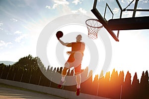 Young man jumping and making a fantastic slam dunk playing stree