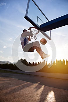 Young man jumping and making a fantastic slam dunk playing stree