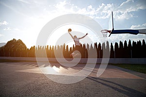 Young man jumping and making a fantastic slam dunk playing stree