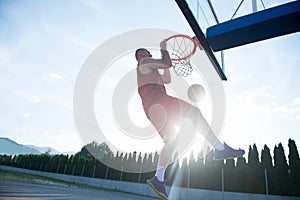 Young man jumping and making a fantastic slam dunk playing stree