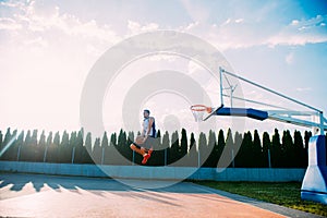 Young man jumping and making a fantastic slam dunk playing stree