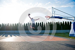 Young man jumping and making a fantastic slam dunk playing stree