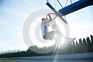 Young man jumping and making a fantastic slam dunk playing stree