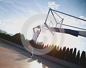 Young man jumping and making a fantastic slam dunk playing stree