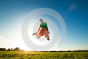 Young man jumping on meadow with dandelions