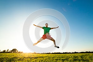 Young man jumping on meadow with dandelions