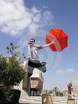 Young man jumping with a red umbrella