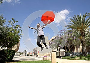 Young man jumping with a red umbrella