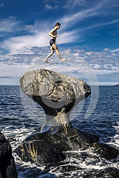 Young man is jumping on stone, Kannesteinen, Norway