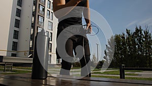 A young man jumps on a skipping rope and stops to talk on a smartphone.