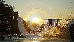 Young man jumps in swimming pool water at Sunset through the sun with lens flare effects. slow motion. 1920x1080