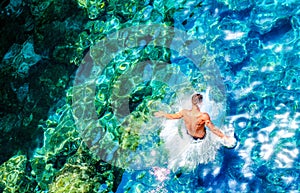 A young man jumps into the turquoise water