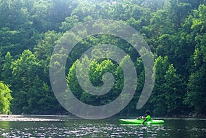 Young man kayaking alone on scenic river