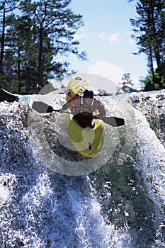 Young man kayaking down waterfall