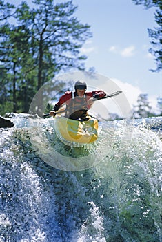 Young man kayaking on waterfall