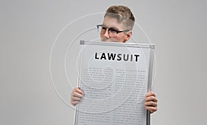 Young man keeps in front of him a poster with the inscription lawsuit isolated on a light background