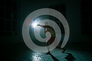 The young man kickboxing on black background