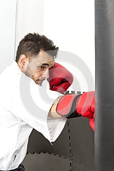 Young man in kimono throwing punches at a heavy punching