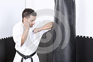 Young man in kimono throwing punches at a heavy punching bag