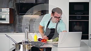 Young man in kitchen coo using laptop listen chef teacher. Realtime