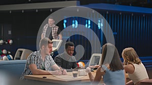 A young man knocks out a strike in a bowling alley and runs up to his friends to rejoice together and give five Together