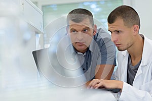 Young man on labcoat showing information to supervisor