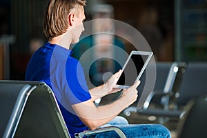 Young man with laptop at the airport while waiting