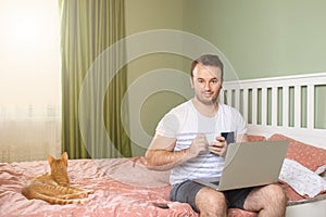Cheerful young adult working from his apartment bed