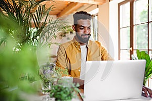 Young man with laptop and coffee working indoors, home office concept.