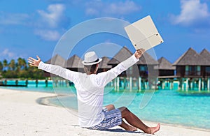 Young man with laptop enjoying vacation near water