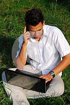 Young man with laptop on the grass