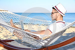 Young man with laptop resting in hammock