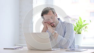 Young Man with Laptop Taking Nap in Office