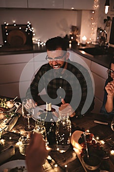 Young man laughing during a candlelit dinner party with friends