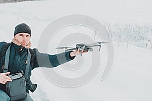 A young man launches a drone into the air in winter in the forest