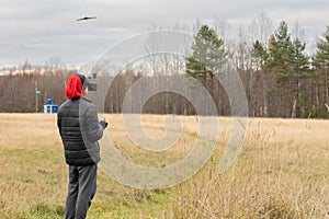 Young man launches rc plane into sky. Teenager with glasses playing with toy radio-controlled airplane outdoors. Boy