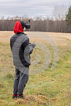 Young man launches rc plane into sky. Teenager with glasses playing with toy radio-controlled airplane outdoors. Boy