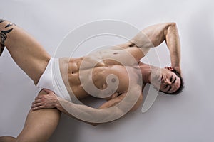 Young man laying on the floor with naked muscular body