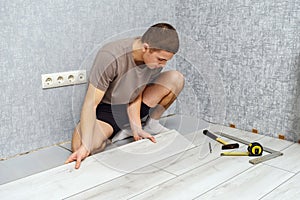 Young man is laying wooden panel of laminate floor