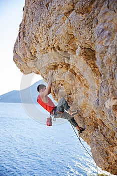 Young man lead climbing on overhanging cliff