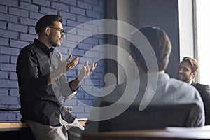 Young man leader hold briefing for team employees in office