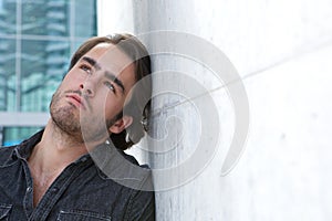 Young man leaning against wall and looking up