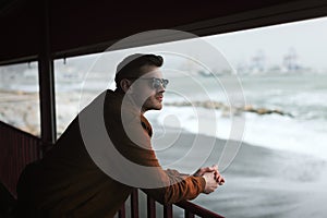 Young man leaning on the railing in front of the beach