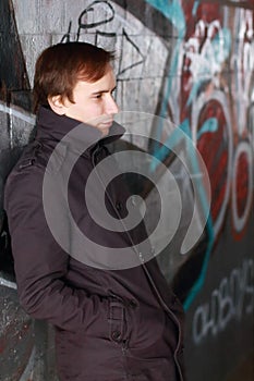 Young man leans back on wall with graffiti