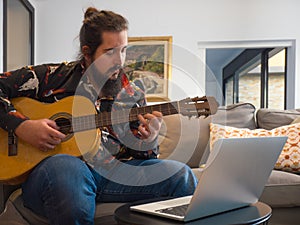 young man learning online guitar lessons