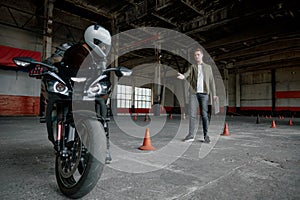 Young man learning to ride bike at private school maneuvering between cones