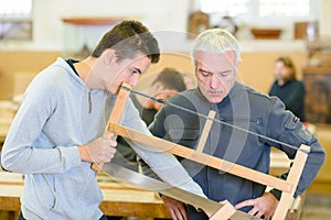 young man learns from luthier master in saw lesson
