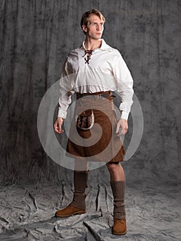 A young man in a leather kilt and a white lace-up blouse. A Scottish knight