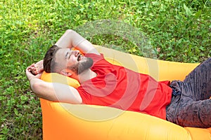 A young man lies on an air mattress, smiles, dreams and rests. Pleasant pastime, relaxation in nature